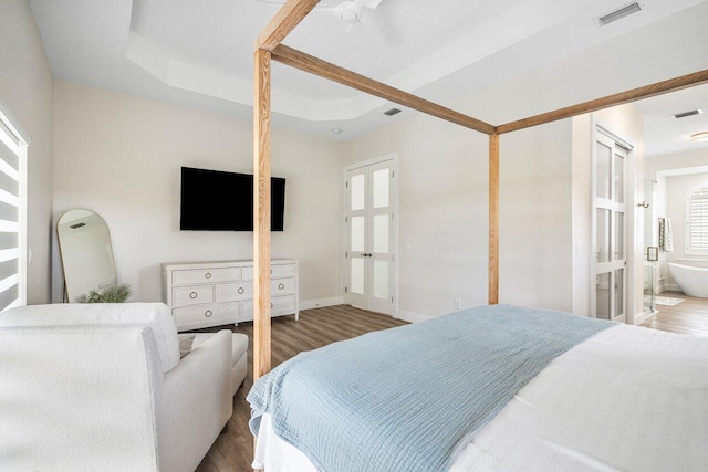 bedroom with hardwood / wood-style flooring, ensuite bath, and multiple windows