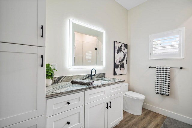 bathroom with a shower, wood-type flooring, vanity, and toilet