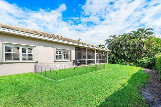 rear view of property featuring a sunroom and a yard