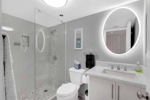 bathroom with vanity, toilet, and tiled shower