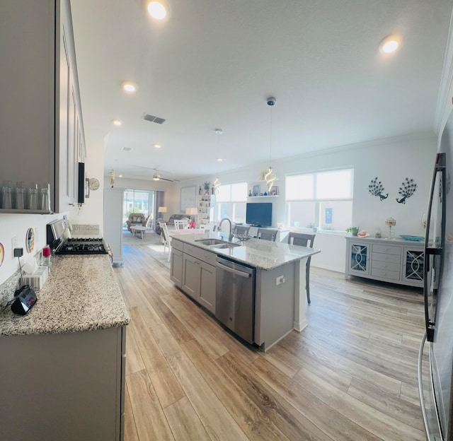 kitchen featuring gray cabinetry, a center island with sink, hanging light fixtures, light hardwood / wood-style flooring, and appliances with stainless steel finishes