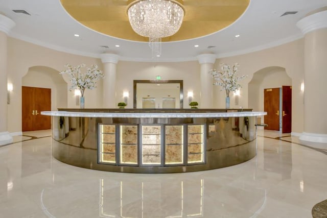 welcome area featuring ornate columns and a chandelier