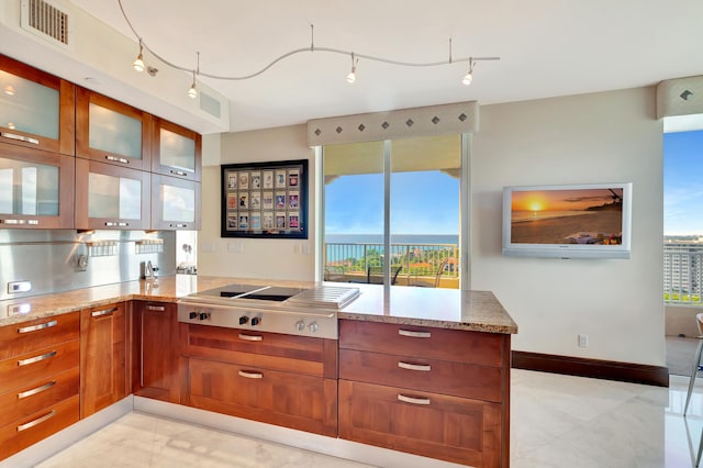 kitchen featuring light stone countertops, a healthy amount of sunlight, and gas cooktop