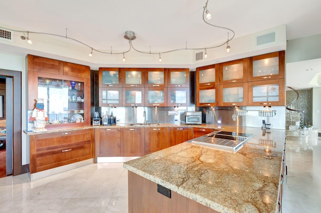 kitchen featuring light stone countertops, sink, and black electric cooktop