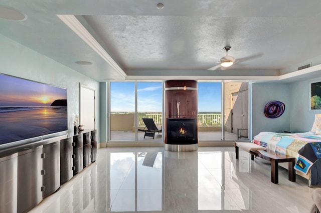 bedroom featuring ceiling fan, a tray ceiling, access to exterior, a textured ceiling, and ornamental molding