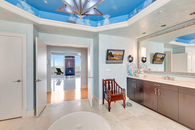 bathroom featuring a tub, crown molding, vanity, and a raised ceiling