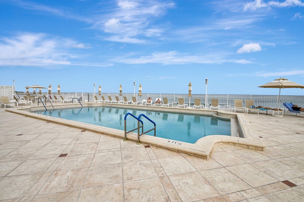 view of swimming pool with a water view and a patio