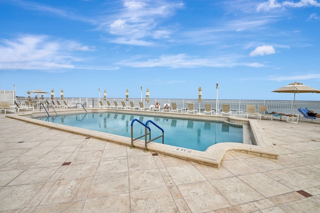 view of swimming pool with a water view and a patio