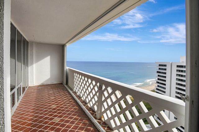 balcony with a water view and a view of the beach