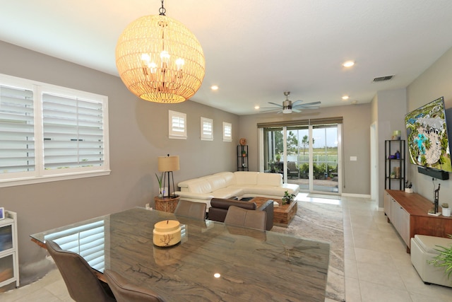 tiled dining area with ceiling fan with notable chandelier