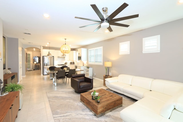 tiled living room featuring ceiling fan with notable chandelier