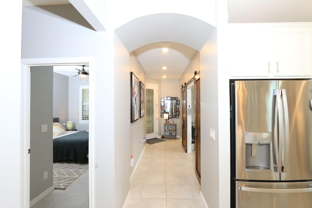 hallway with a barn door and light tile patterned flooring