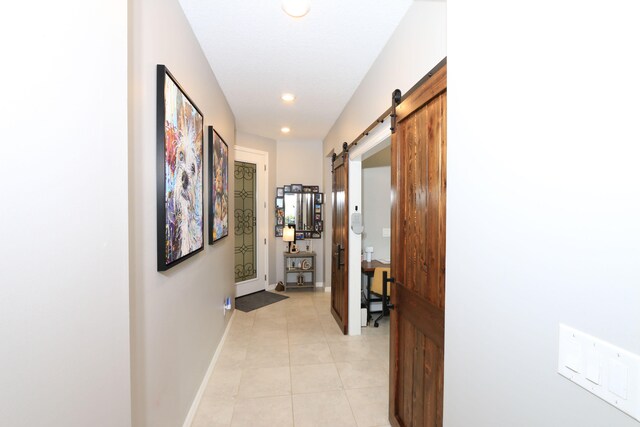 hallway featuring a barn door and light tile patterned floors