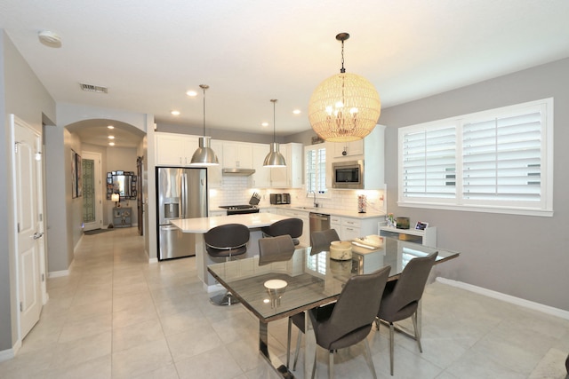 tiled dining space featuring sink and an inviting chandelier