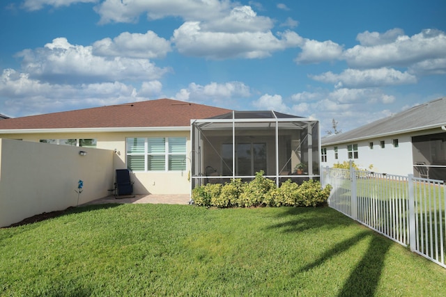 rear view of house with glass enclosure, a sunroom, and a yard