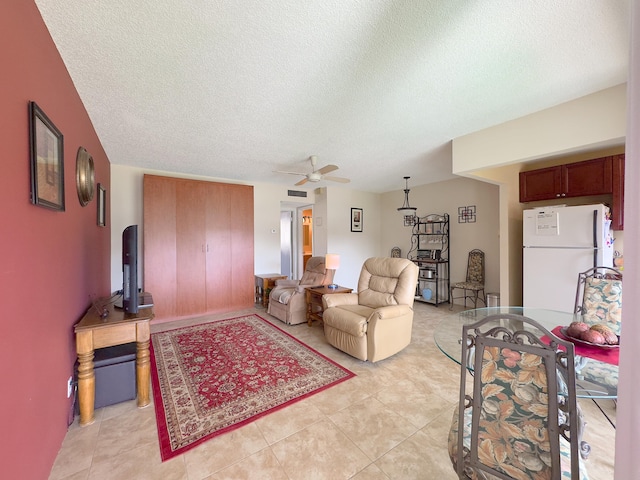 tiled living room featuring ceiling fan and a textured ceiling