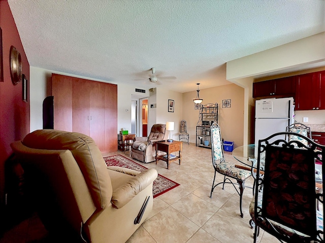 living room with ceiling fan, light tile patterned floors, and a textured ceiling