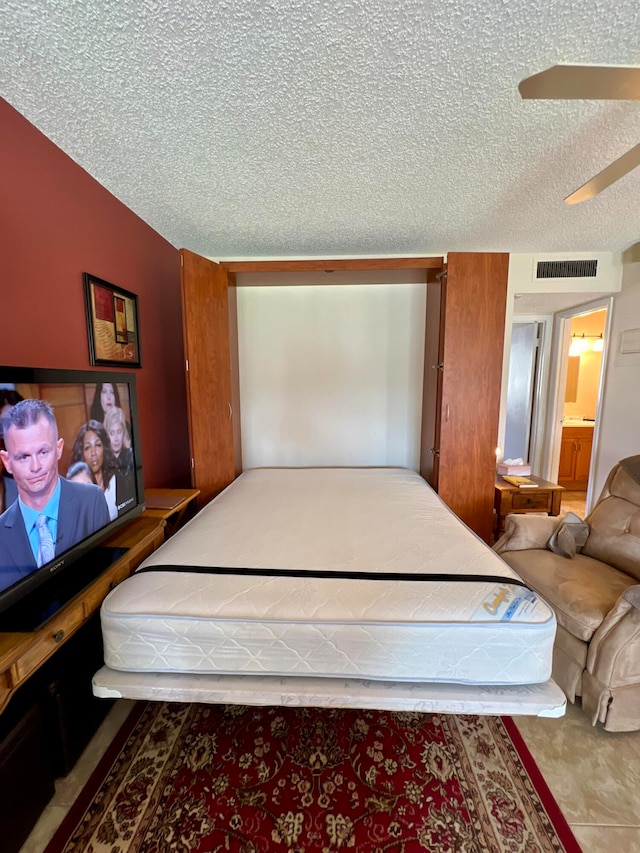 bedroom featuring ceiling fan, a textured ceiling, and connected bathroom