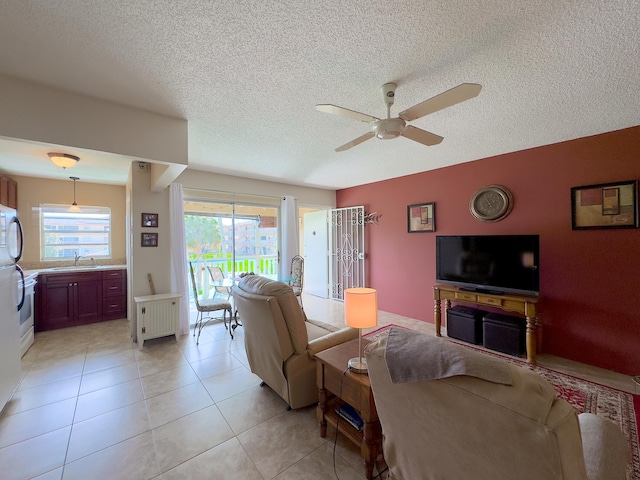 tiled living room featuring ceiling fan, a textured ceiling, plenty of natural light, and sink