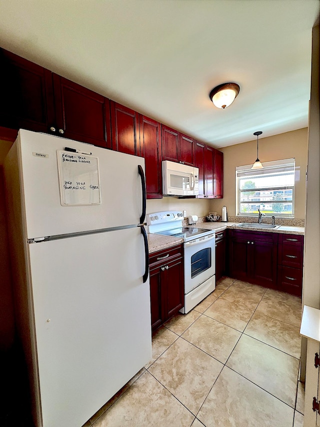 kitchen featuring light tile patterned floors, white appliances, hanging light fixtures, and sink