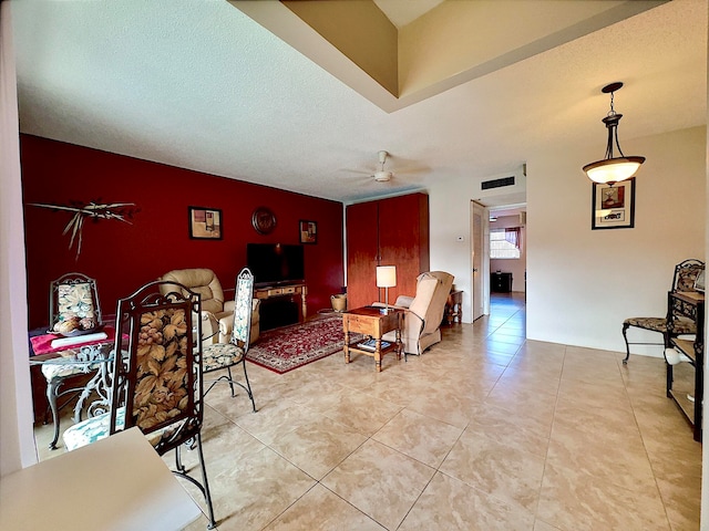 living room featuring ceiling fan, light tile patterned flooring, and a textured ceiling