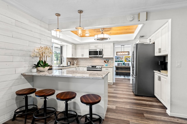 kitchen featuring stainless steel appliances, white cabinetry, sink, light stone counters, and kitchen peninsula