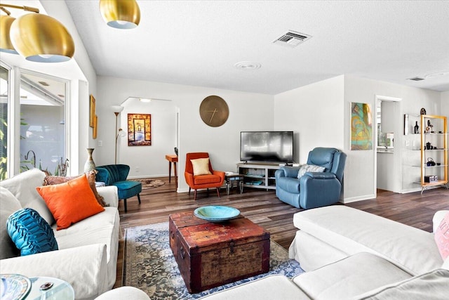 living room with a textured ceiling and dark hardwood / wood-style floors