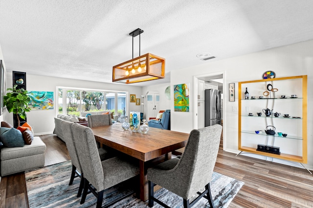 dining area with hardwood / wood-style flooring and a textured ceiling