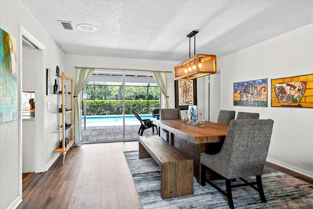 dining area featuring dark wood-type flooring and a textured ceiling