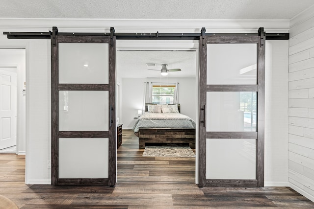 bedroom with dark hardwood / wood-style flooring, a barn door, and a textured ceiling