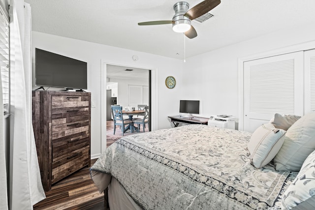 bedroom with a textured ceiling, dark hardwood / wood-style flooring, ceiling fan, and a closet