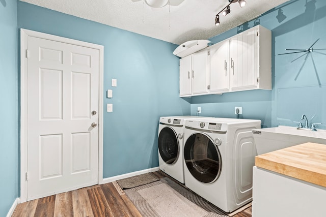 clothes washing area featuring cabinets, wood-type flooring, washing machine and clothes dryer, and a textured ceiling