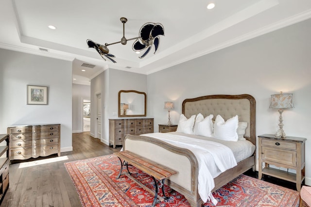 bedroom with dark hardwood / wood-style floors, a raised ceiling, and crown molding