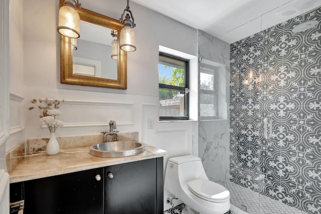 bathroom with a tile shower, vanity, and toilet