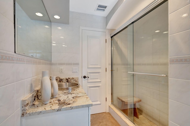 bathroom featuring tile patterned floors, vanity, tile walls, and walk in shower