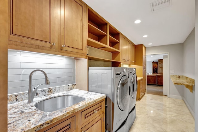 laundry room with cabinets, washer and clothes dryer, and sink