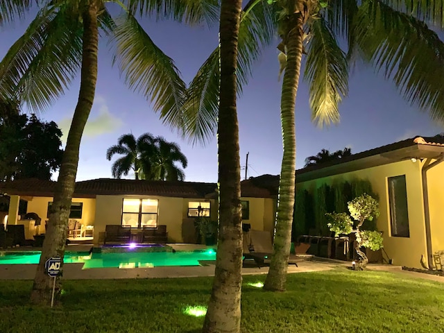 back house at dusk with a yard and a patio