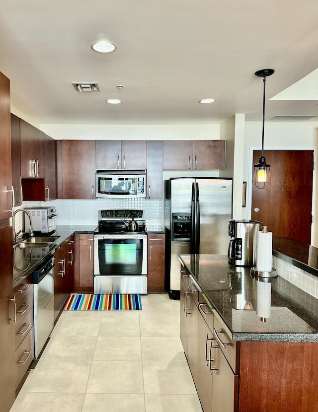 kitchen with pendant lighting, sink, light tile patterned floors, tasteful backsplash, and stainless steel appliances