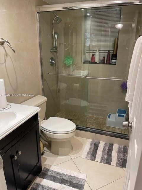 bathroom featuring toilet, vanity, tile patterned flooring, and walk in shower