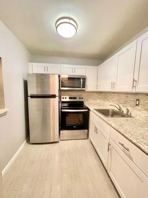 kitchen featuring white cabinets, decorative backsplash, stainless steel appliances, and sink