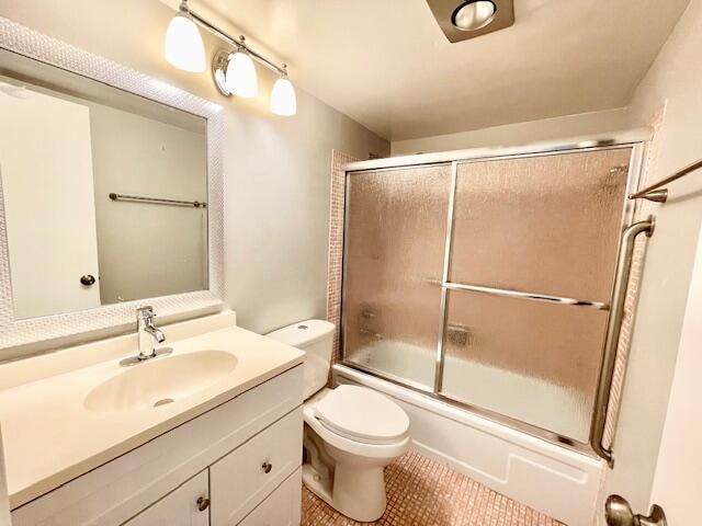 full bathroom with shower / bath combination with glass door, tile patterned floors, vanity, and toilet