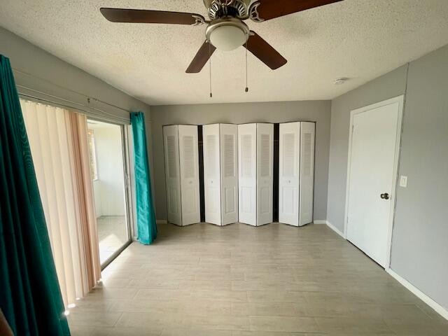 unfurnished bedroom featuring ceiling fan, a textured ceiling, light hardwood / wood-style flooring, and two closets