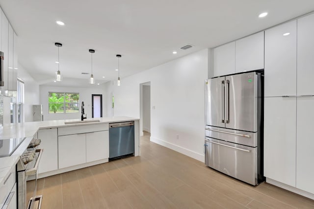 kitchen featuring light hardwood / wood-style floors, sink, white cabinetry, appliances with stainless steel finishes, and decorative light fixtures