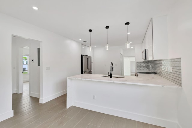 kitchen featuring white cabinetry, sink, appliances with stainless steel finishes, kitchen peninsula, and hanging light fixtures