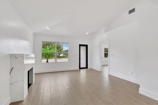 unfurnished living room with light wood-type flooring and lofted ceiling