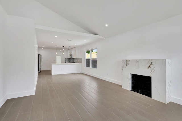 unfurnished living room with a fireplace, wood-type flooring, and vaulted ceiling