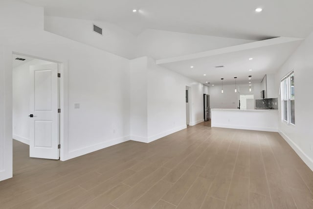 unfurnished living room with light wood-type flooring and lofted ceiling