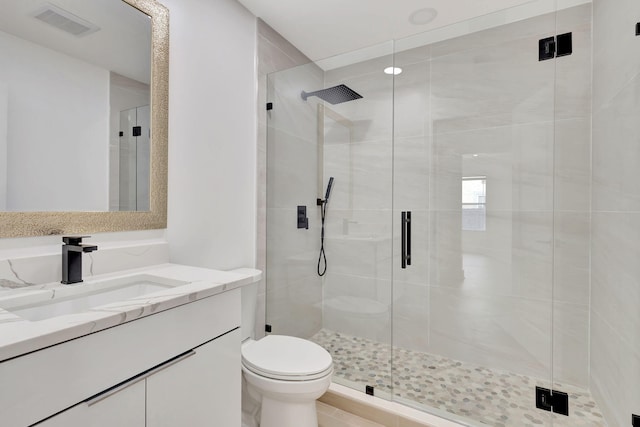 bathroom featuring a shower with shower door, vanity, and toilet