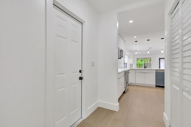 corridor with light hardwood / wood-style floors and sink