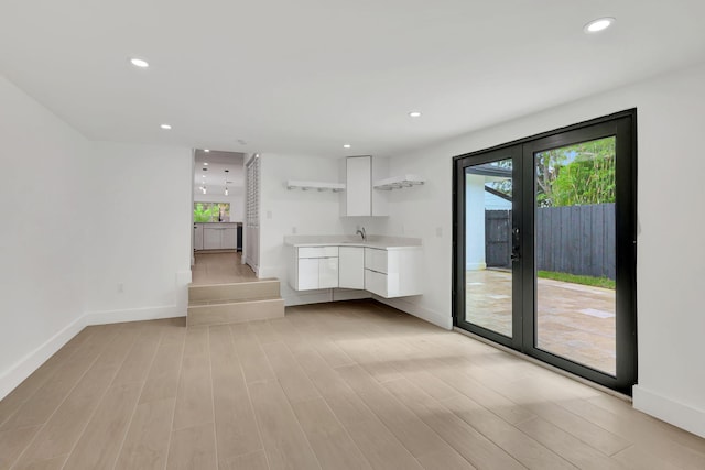 unfurnished living room with light hardwood / wood-style floors and sink